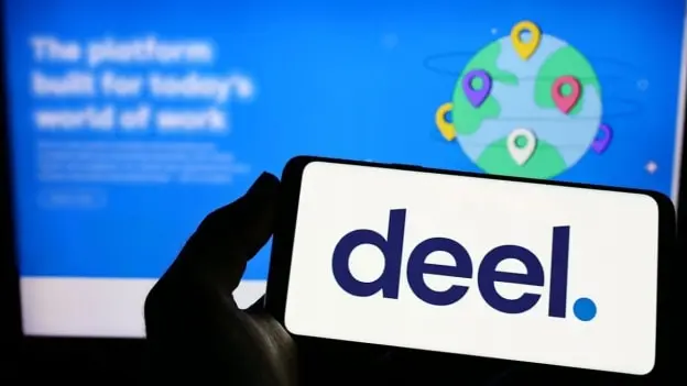 TechDogs-"Deel Logo Displayed On Smartphone Screen Against Blue Background With Global Work Graphic"