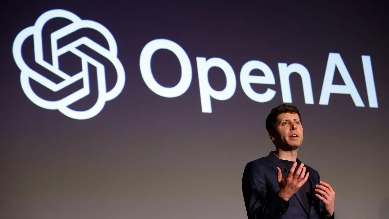 TechDogs-"An Image Of Sam Altman Standing In Front Of The OpenAI Logo"