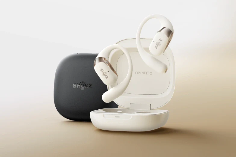 TechDogs-"Gadget 2: Shokz OpenFit 2 Earbuds"-"Shokz OpenFit 2 Earbuds In Black Inside Open Charging Case Placed On A Smooth White Fabric Background With Closed Case Nearby""